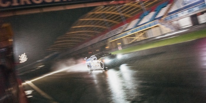 Raceauto met brandende koplampen op het natte TT Circuit Assen in het donker